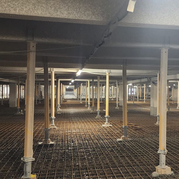 Baugrube mit Stahlbewehrung und zahlreichen vertikalen Stützen unter einer Betondecke